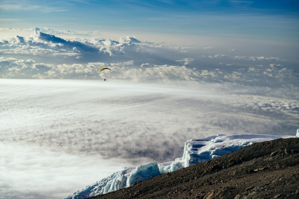  Ein Gleitschirmpilot fliegt über den Kilimandscharo. Eine Expedition von Altezza Travel